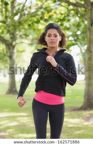 Portrait of a beautiful healthy young woman in black jacket jogging in the park