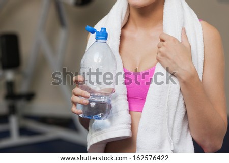 Close up mid section of a sporty woman with water bottle in the gym