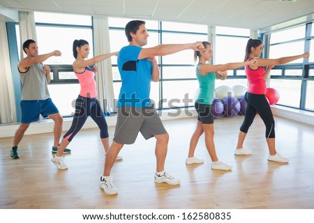 Full length of sporty people doing power fitness exercise at yoga class