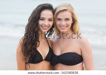 Portrait of two smiling young bikini women at the beach