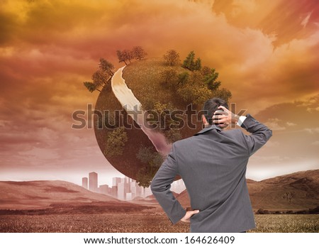 Composite image of young businessman standing back to camera scratching his head