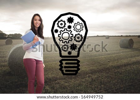 Composite image of student standing in a computer room and holding a folder while smiling