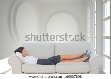 Composite image of smiling business woman lying down on the couch in the office