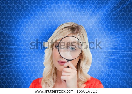 Composite image of fair-haired woman looking through a magnifying glass