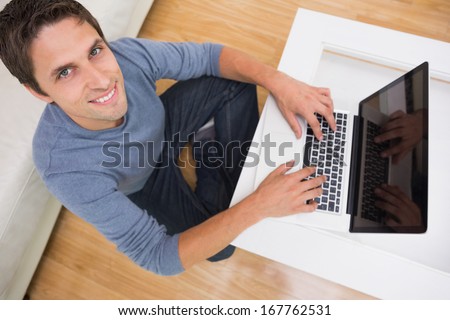 Overhead portrait of a young man using laptop in living room at home