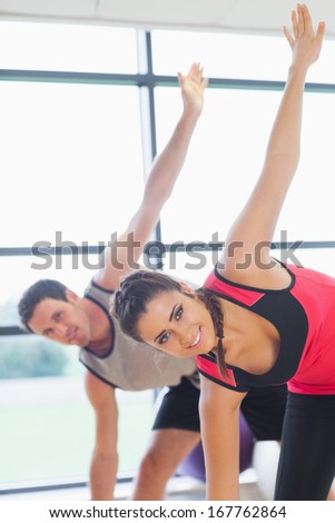 Portrait of two sporty people stretching hands at yoga class in fitness studio