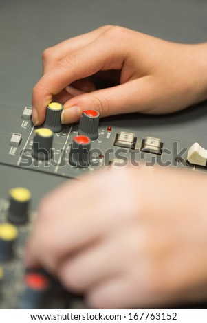 Hands working on a sound mixing desk in studio in college