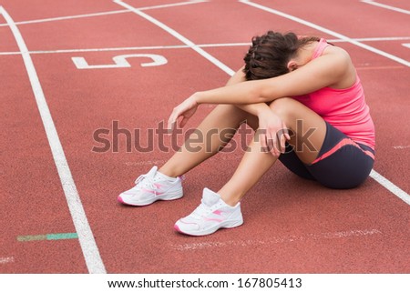 Full Length Of A Tensed Sporty Woman Sitting On The Running Track