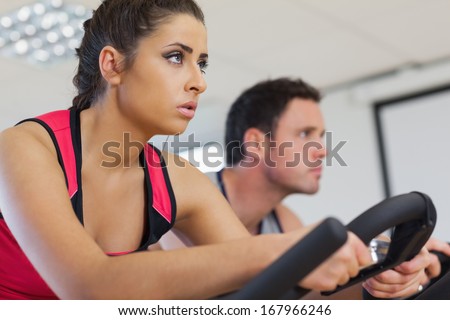 Side view of a young man and woman working out at class in gym