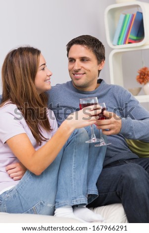 Smiling young couple toasting wine glasses on sofa at home