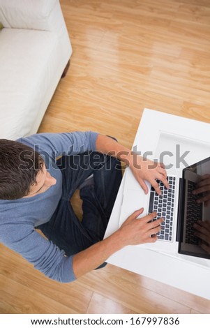 Overhead view of a young man using laptop in living room at home