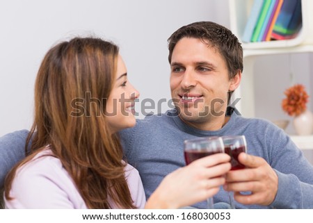 Close-up of a smiling young couple toasting wine glasses at home