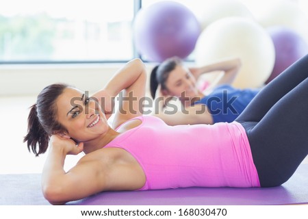 Two fit young women doing pilate exercises in fitness studio
