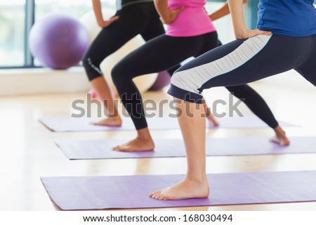 Low section of class and instructor doing stretching pilate exercises in fitness studio