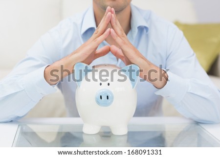 Close-up mid section casual man with piggy bank in the living room at home