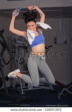 Full length portrait of fit young woman jumping in the gym