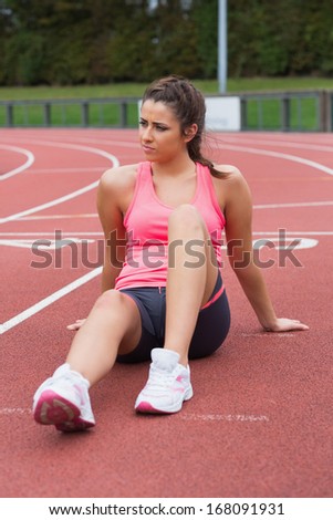 Full length of a young sporty woman sitting on the running track