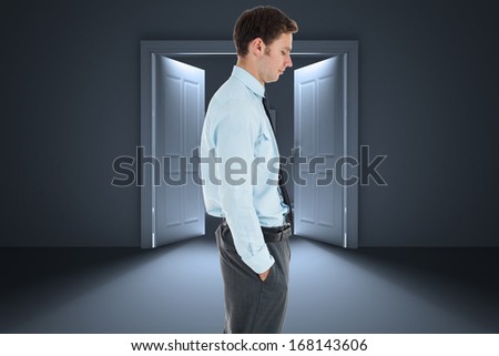 Serious businessman standing with hand in pocket against door opening in dark room