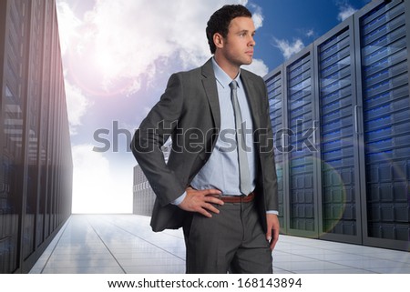 Businessman with hand on hip against server hallway in the sky