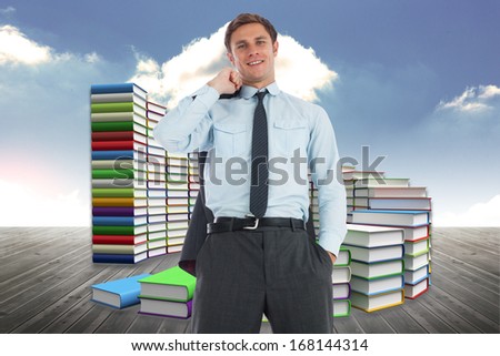 Smiling businessman holding his jacket against steps made of books against sky