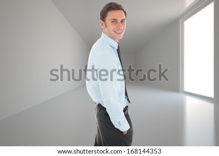Happy businessman standing with hand in pocket against bright hall with windows