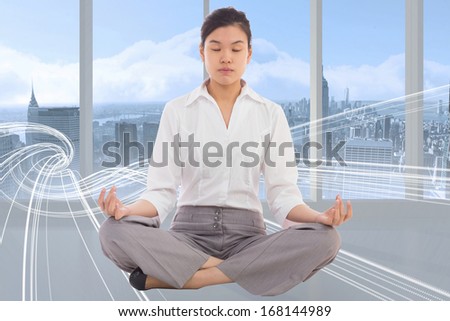 Businesswoman sitting in lotus pose against white design in room