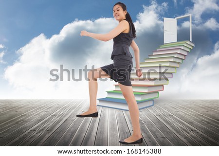 Businesswoman stepping up against book steps leading to door against sky