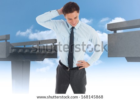 Thinking businessman scratching head against unfinished bridge