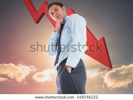 Thoughtful businessman with hand on chin against red arrow pointing down against sky