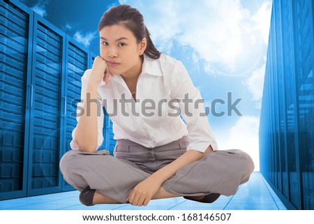 Grumpy businesswoman sitting cross legged against server hallway in the blue sky