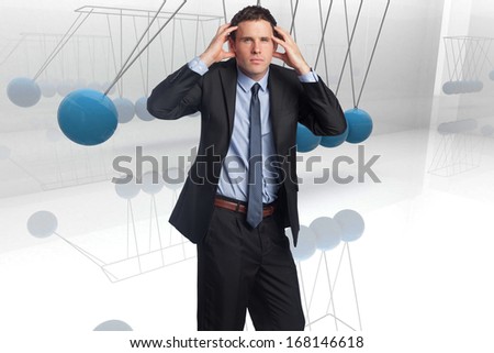 Stressed businessman with hands on head against blue newtons cradle
