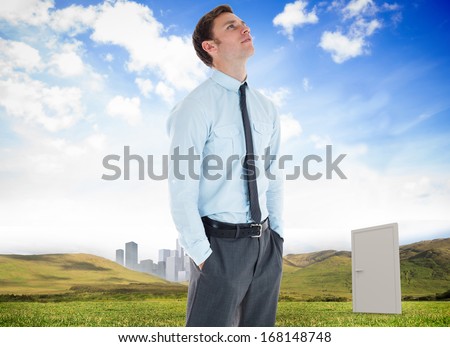 Serious businessman standing with hands in pockets against closed doors in a meadow