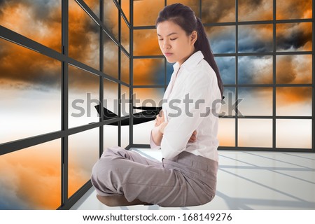 Businesswoman sitting cross legged with arms crossed against airplane flying over orange sky past window