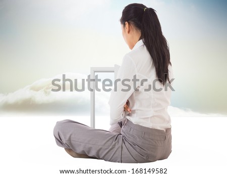 Businesswoman sitting cross legged against opening door in sky