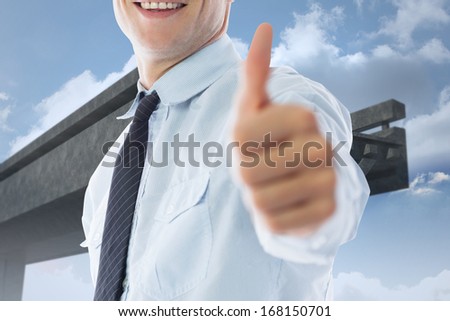 Businessman showing thumbs up against unfinished bridge