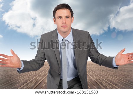 Businessman posing with hands out against cloudy sky background