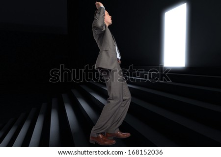 Businessman posing with hands up against steps leading to light in the darkness