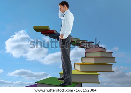Thoughtful businessman with hand on head against book steps against sky