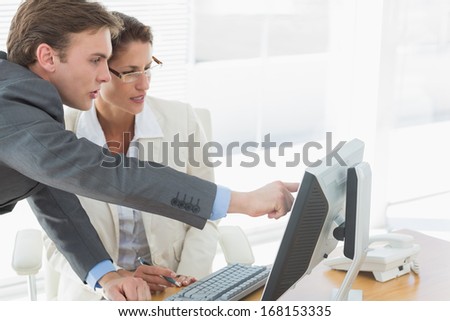 Side view of smartly dressed business couple using computer at office desk