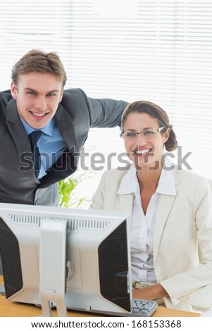 Portrait of a confident smiling business couple with computer in a bright office