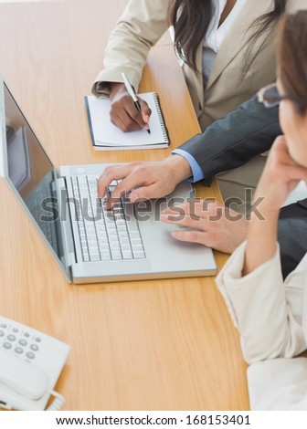 Close-up side view of business colleagues using laptop at office desk