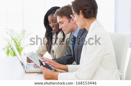 Side view of business colleagues using laptop and digital tablet at office desk