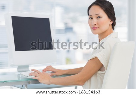 Portrait of a young businesswoman using computer in a bright office