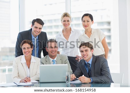 Group of happy business colleagues with laptop at office desk