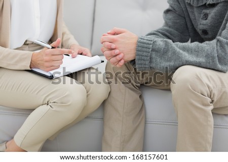 Close-up mid section of a financial adviser writing notes with man at home