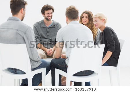 Group therapy in session sitting in a circle with therapist