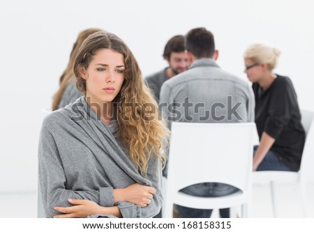 Group therapy in session sitting in a circle with therapist while woman in foreground