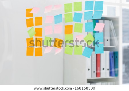 Close-up of colorful sticky notes on glass wall at the office