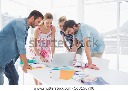 Young casual business people using laptop together in a bright office