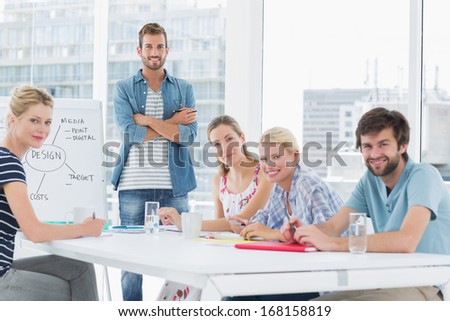 Young casual business people sitting around conference table in a bright office